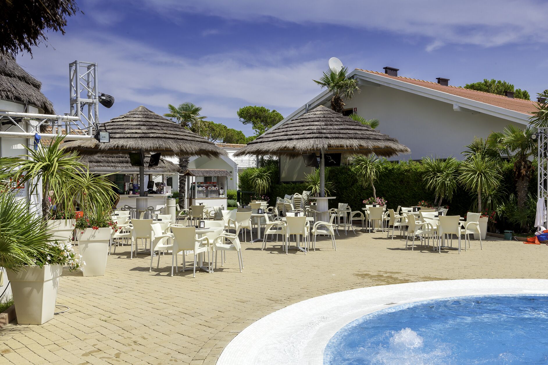 A beachside resort with outdoor seating, thatched umbrellas, and a swimming pool.