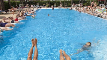 Una piscina al aire libre, sombrillas, sillones reclinables de piscina