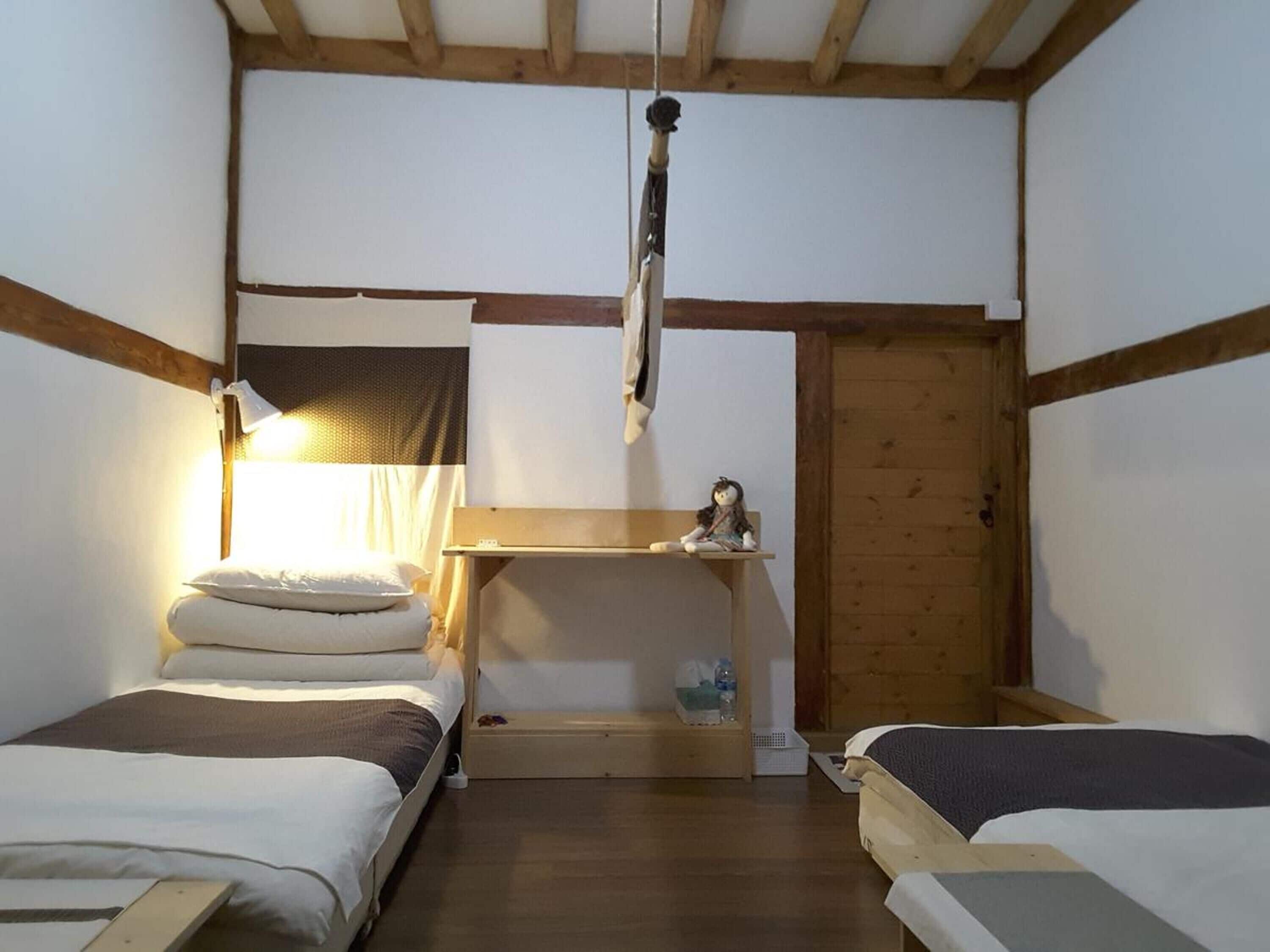 Ein kleines, gemütliches Zimmer mit zwei Einzelbetten, einem Schreibtisch und einer Pendelleuchte.