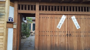 A wooden gate with a number sign and two signs on it. - Yettle Hanok Stay (Gyeongju)
