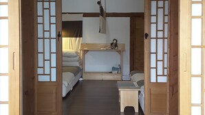 A traditional Japanese-style room with tatami flooring, a low wooden bed, a small table, and a hanging lantern. - Yettle Hanok Stay (Gyeongju)
