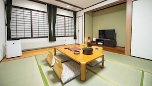 A traditional Japanese room with tatami flooring, a low wooden table, a television, and sliding doors. - Hotel Kinwaso (Sapporo)