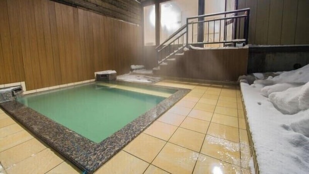 A hot spring bath with a wooden interior, tiled floor, and a staircase leading to a higher level. - Hotel Kinwaso (Sapporo)