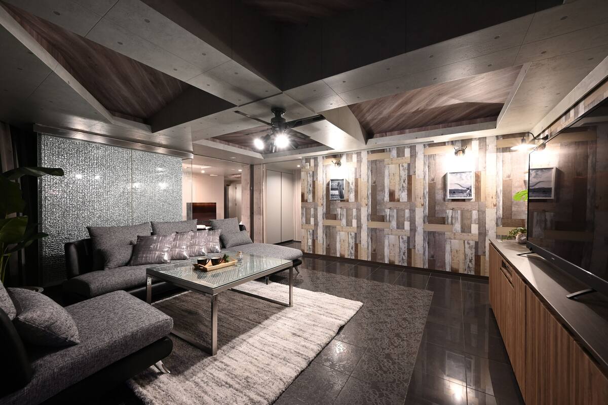 A modern living room with a sectional sofa, a glass coffee table, and a wooden accent wall.