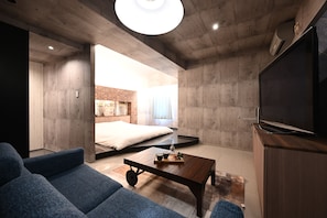 A modern living room with a sofa, a coffee table, and a TV. - Hotel The Scene  (Yokohama)