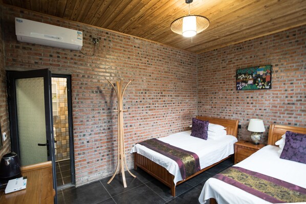 Une chambre avec deux lits, un plafond en bois, des murs en briques et un tableau accroché au mur.
