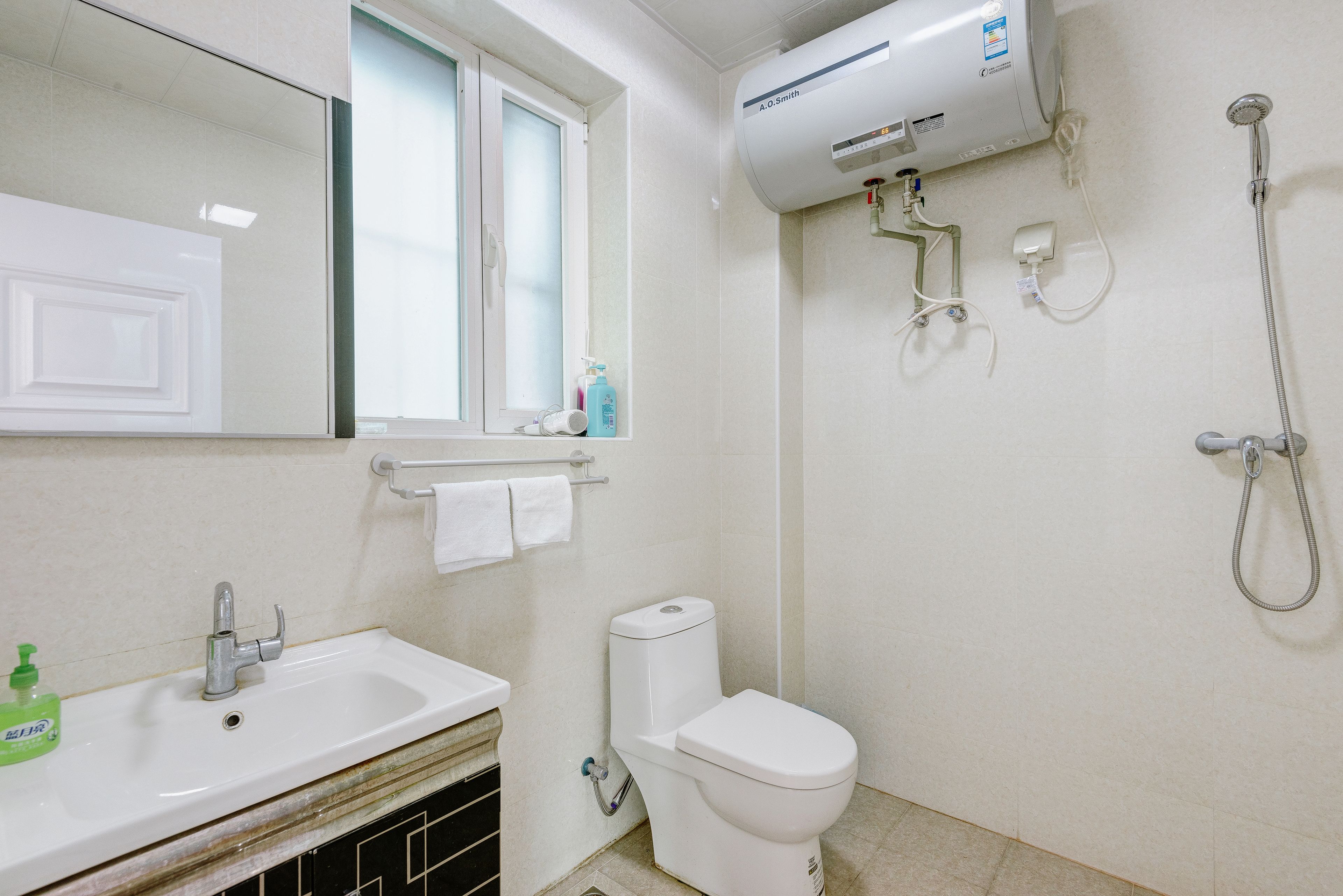 Un baño con lavamanos blanco, inodoro, ventana y ducha.