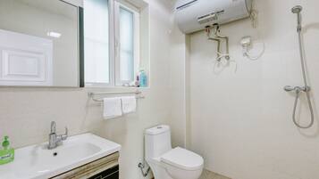 Un baño con lavamanos blanco, inodoro, ventana y ducha.