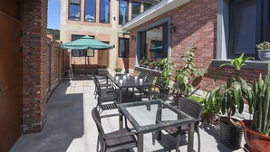 Un patio con mobiliario exterior, un edificio de ladrillo y macetas con plantas.