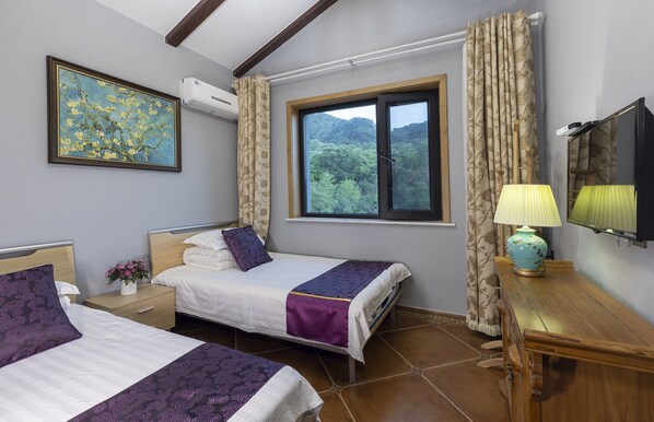 A hotel room with two beds, a window with a view of greenery, a mounted TV, and a bedside table with a lamp. - Mutianyu GreatWall Wangshanyuan Homestay (Huairou)