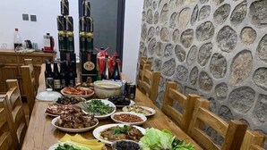 Una mesa de madera con varios platos y botellas de bebidas.