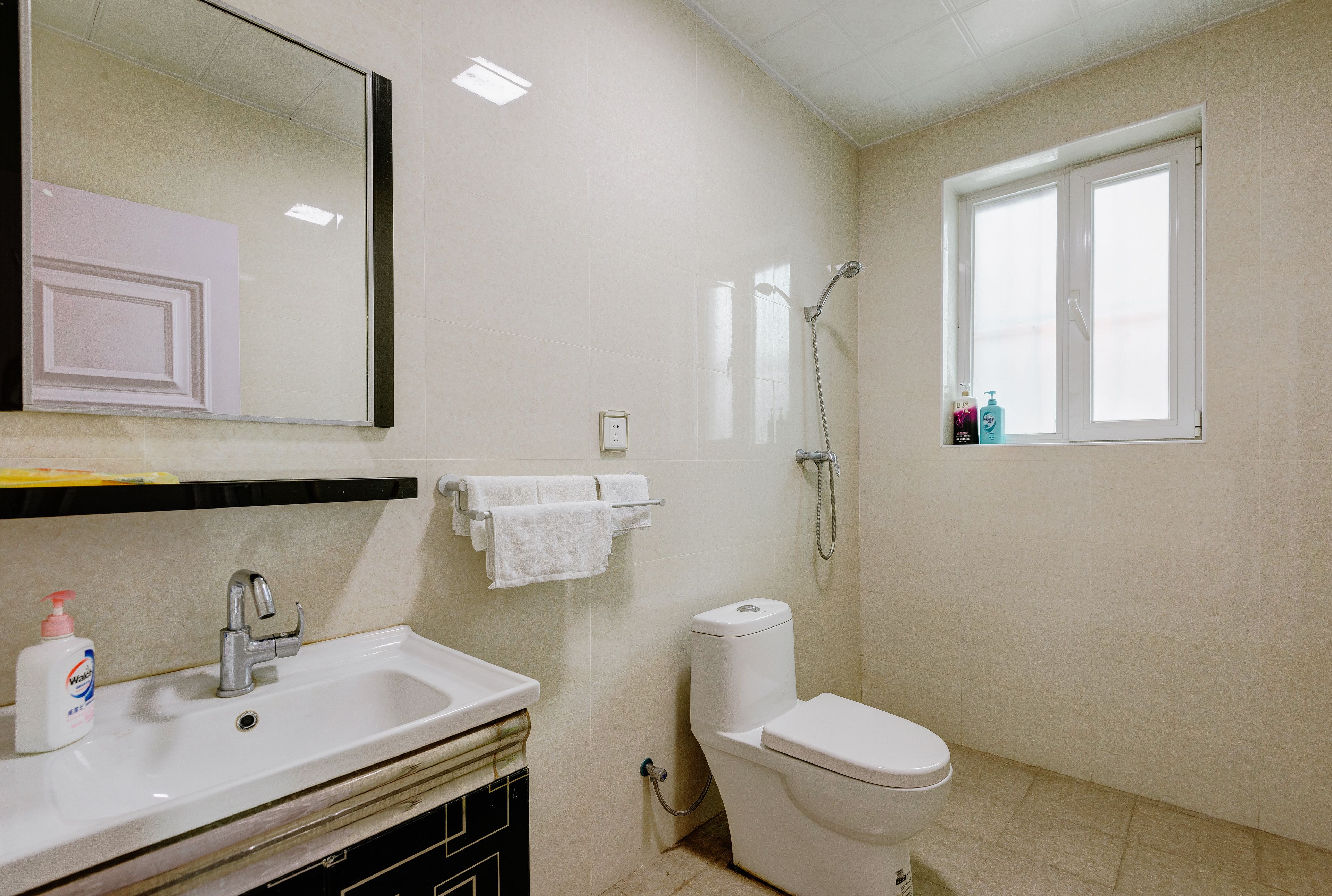 A bathroom with a sink, mirror, toilet, and shower.