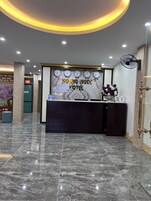 Bancada de recepção de hotel com piso de mármore, um relógio e um ventilador.