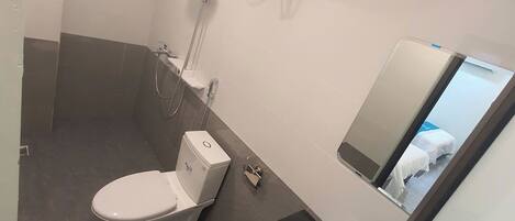 Un baño con inodoro, bidé y espejo.