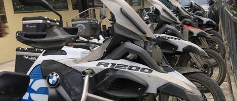 A row of BMW R1200 motorcycles parked in a narrow street.