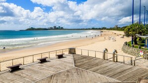 Une plage avec une promenade en bois, des bancs et un poste de surveillance pour les sauveteurs.