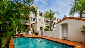 A swimming pool surrounded by palm trees and a building with balconies. - Beachport (Mooloolaba)