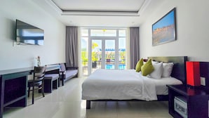 A hotel room with a bed, a desk, a TV, and a balcony with a pool view.