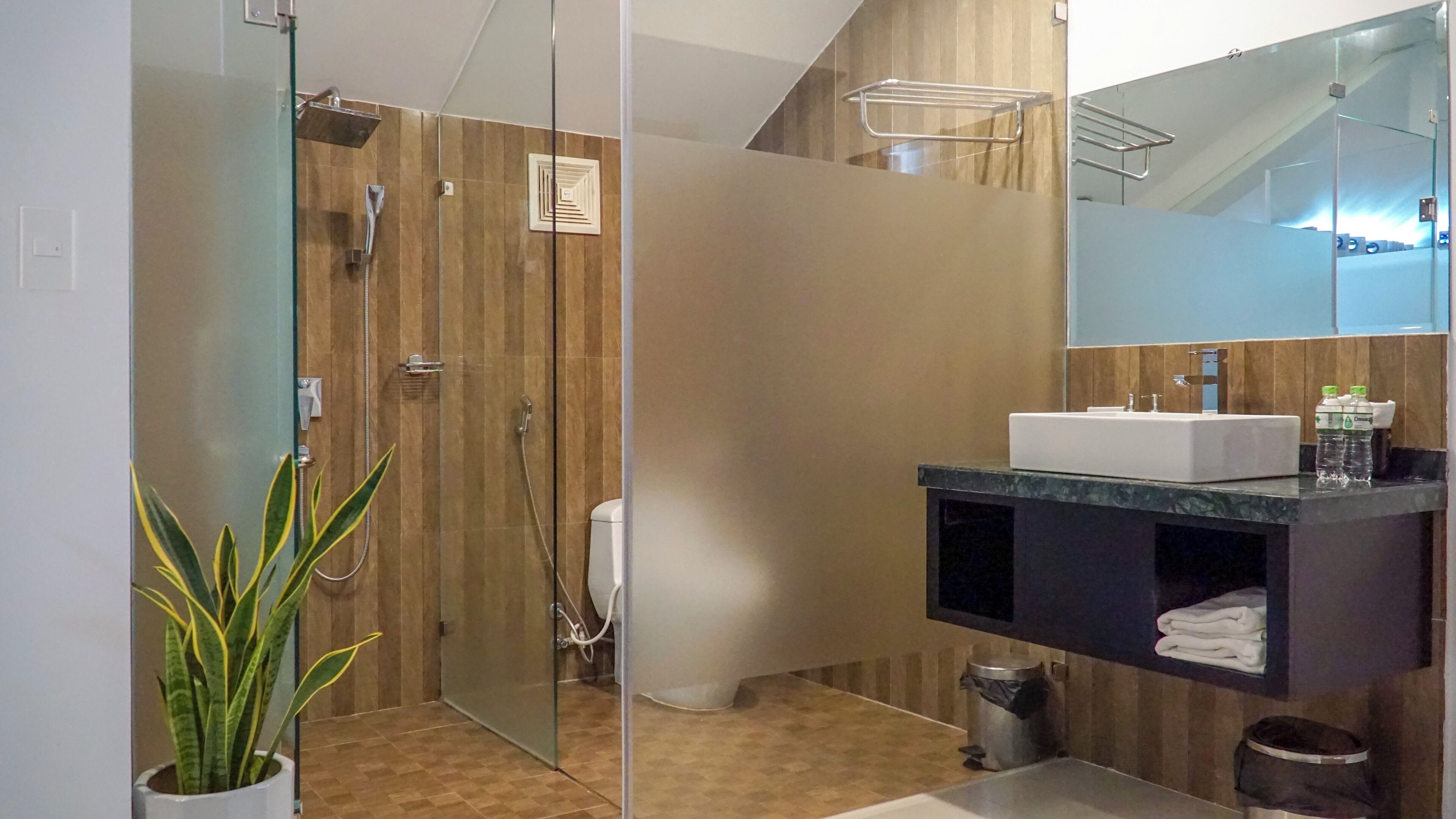 Une salle de bain moderne avec une douche à parois de verre, un lavabo doté d’un plan de travail foncé et un miroir au-dessus du lavabo.