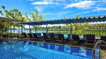 Una piscina al aire libre, sombrillas, sillones reclinables de piscina