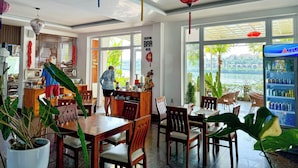 A restaurant with wooden furniture, large windows, and hanging decorative lights.