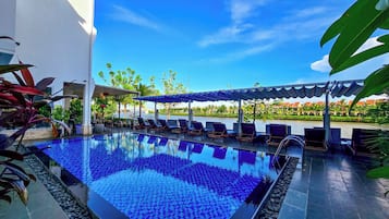 Una piscina al aire libre, sombrillas, sillones reclinables de piscina