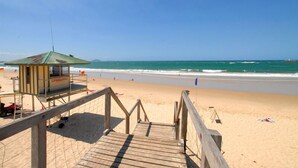 A lifeguard tower on a sandy beach with a wooden walkway leading to it. - Illawong Apartments (Mooloolaba)