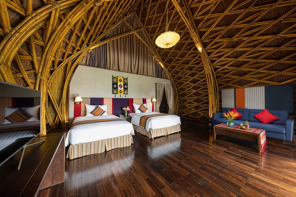 A room with two beds, a sofa, and a wooden floor.