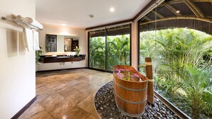 A modern bathroom with a large window, a wooden barrel sink, and a stone floor.