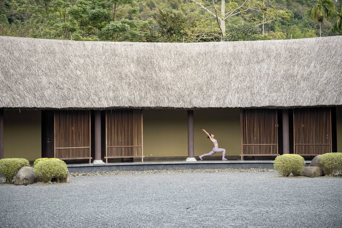 A traditional building with a thatched roof, wooden slats, and a gravel ground.