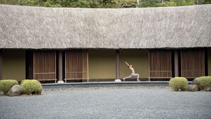 A traditional building with a thatched roof, wooden slats, and a gravel ground.