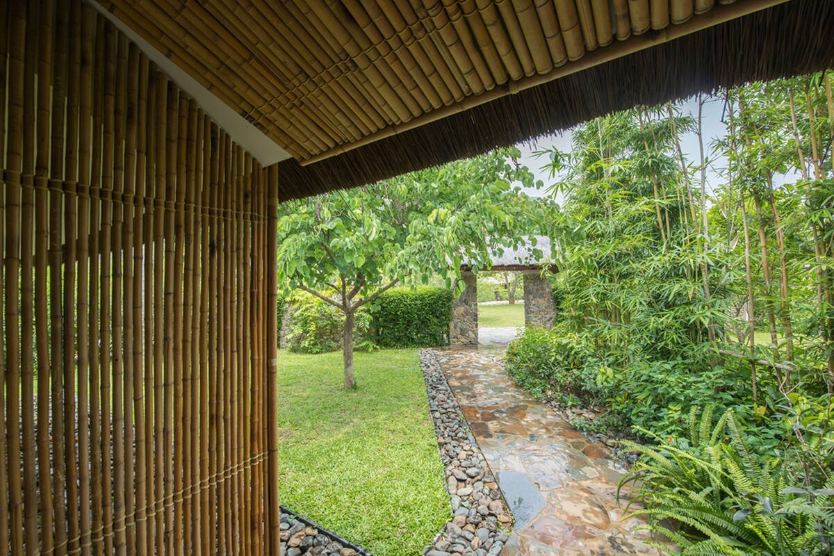 A bamboo structure with a stone pathway leading to a garden area.