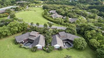Residential homes with thatched roofs surround a central park in a community.