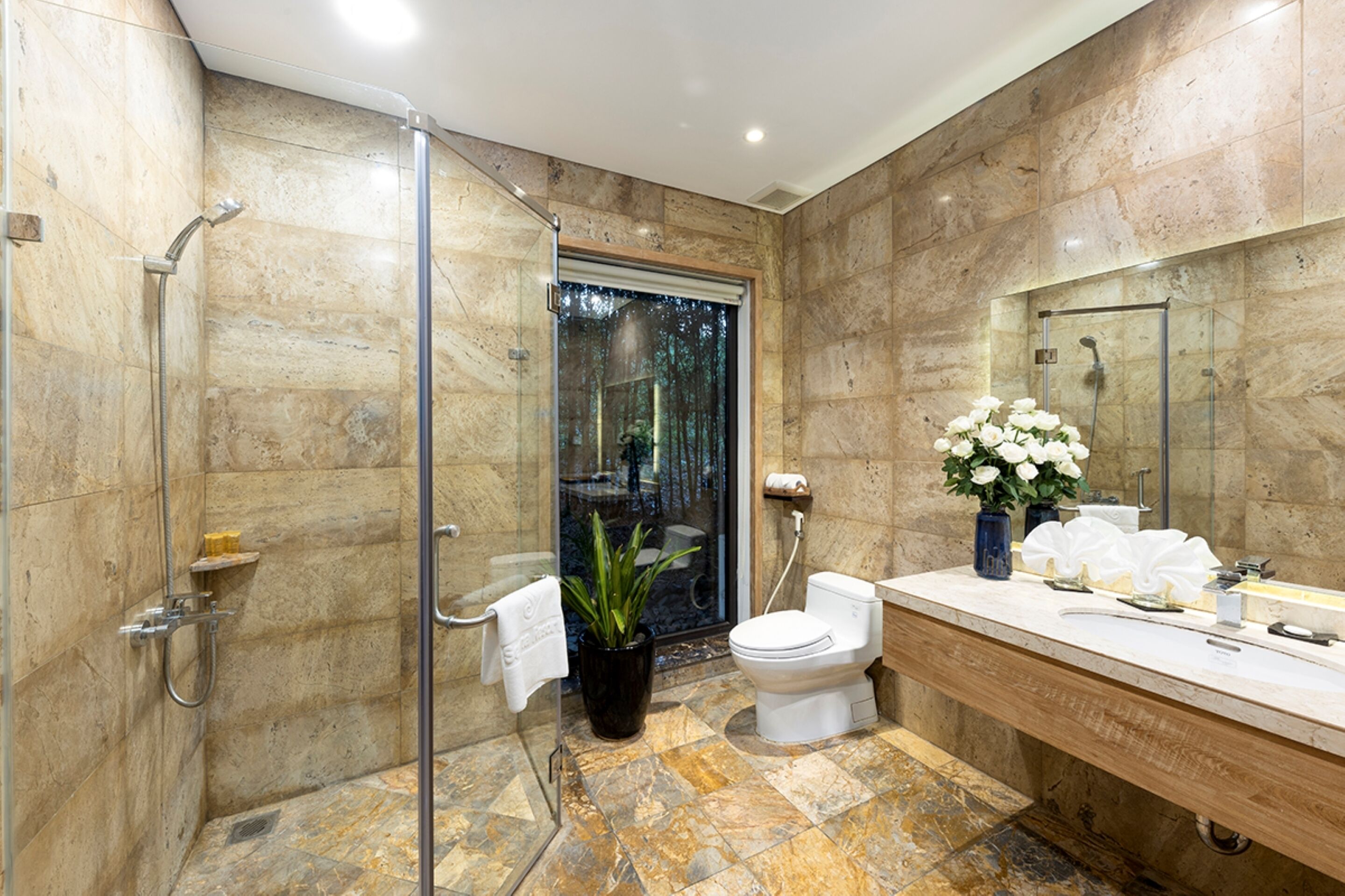 A modern bathroom with a glass shower enclosure, a toilet, and a vanity with a mirror.
