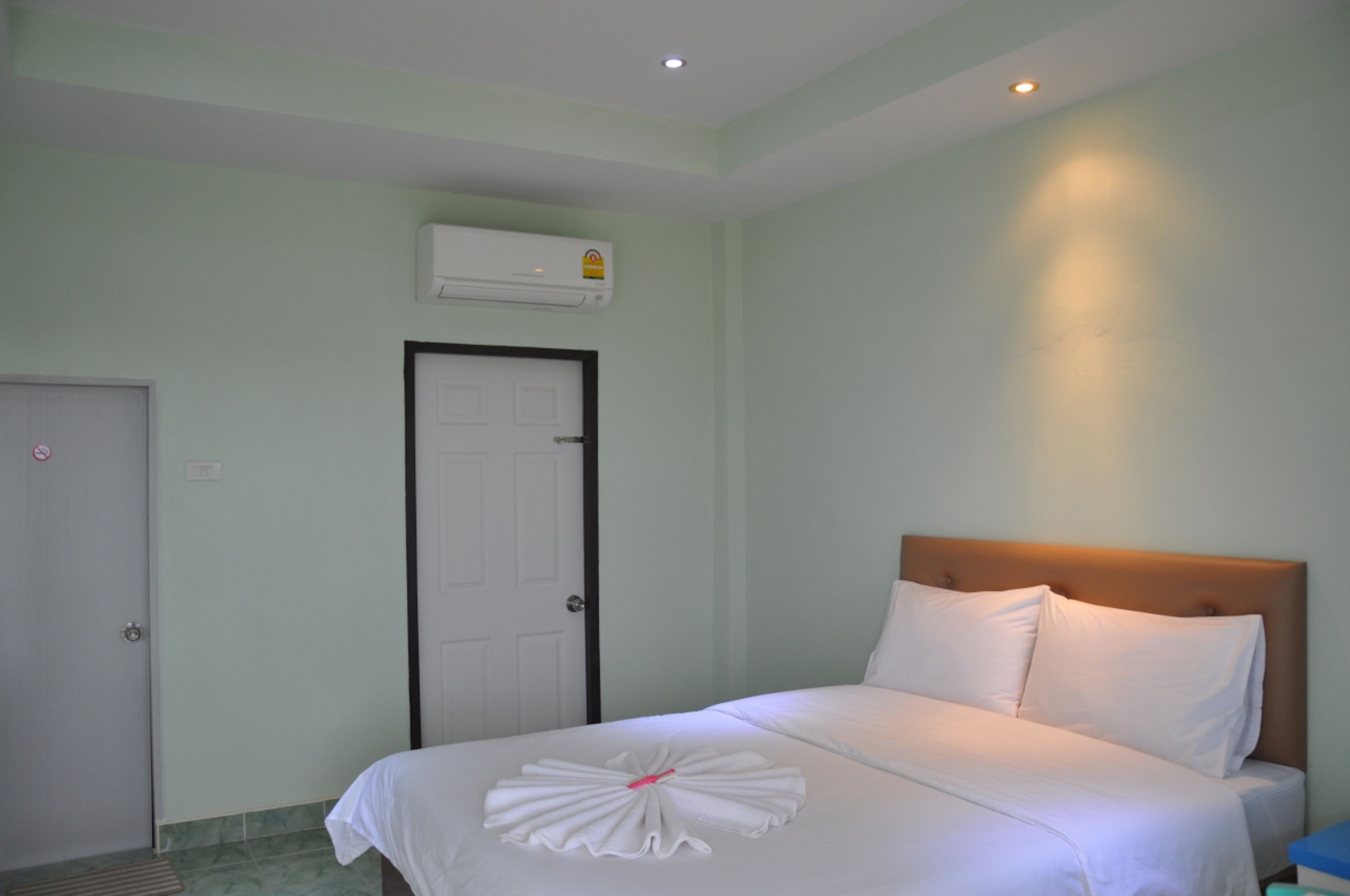 A hotel room with a bed, a door, and an air conditioning unit.