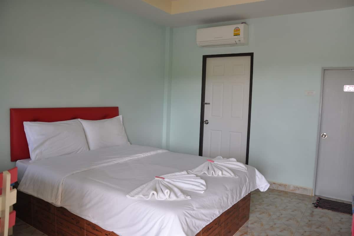 Cama bem arrumada com lençóis e toalhas brancas.