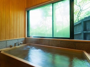 A large, rectangular hot tub with a wooden interior and a window overlooking a wooded area. - Prime Villa Fuki No Sato (Yufu)