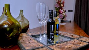 Una mesa con tres jarrones, dos copas de vino y dos botellas.
