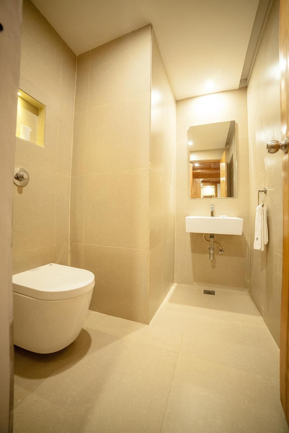 A compact bathroom with a toilet, sink, and mirror.