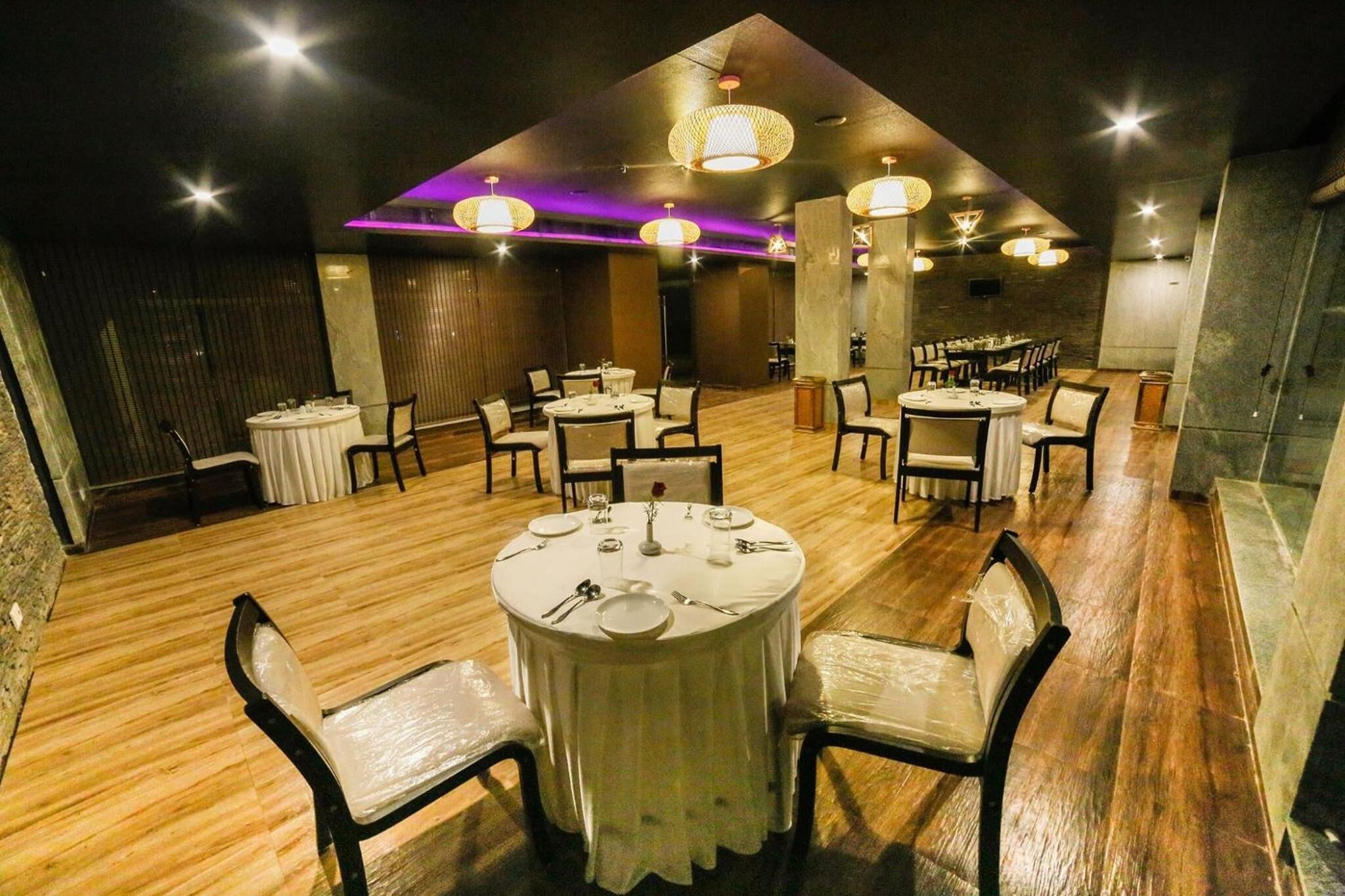 A restaurant with round tables, chairs, and a wooden floor.