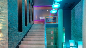A staircase with a modern design, leading to a room with a brick wall and a seating area with chairs. - Vivera Grande (Thindukkal)
