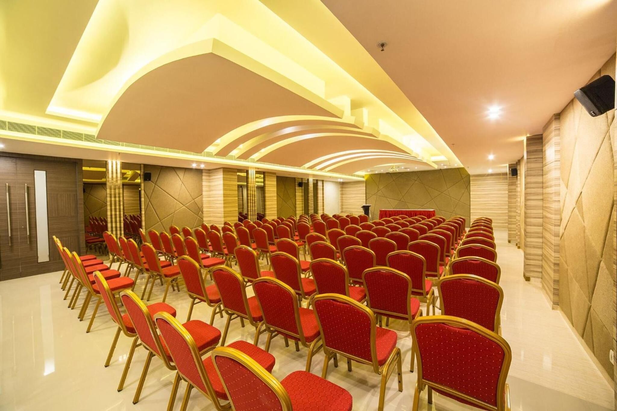 A conference room with rows of red chairs and a stage.