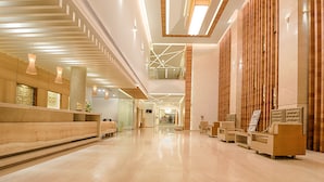A spacious lobby with a high ceiling, modern lighting, and a reception desk. - Vivera Grande (Thindukkal)