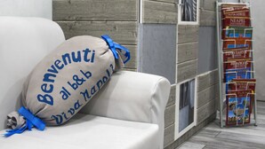 A white sofa with a beige pillow that reads "Benvenuti al b&b" and "Diva Napoli". - B&B Viva Napoli (Naples)