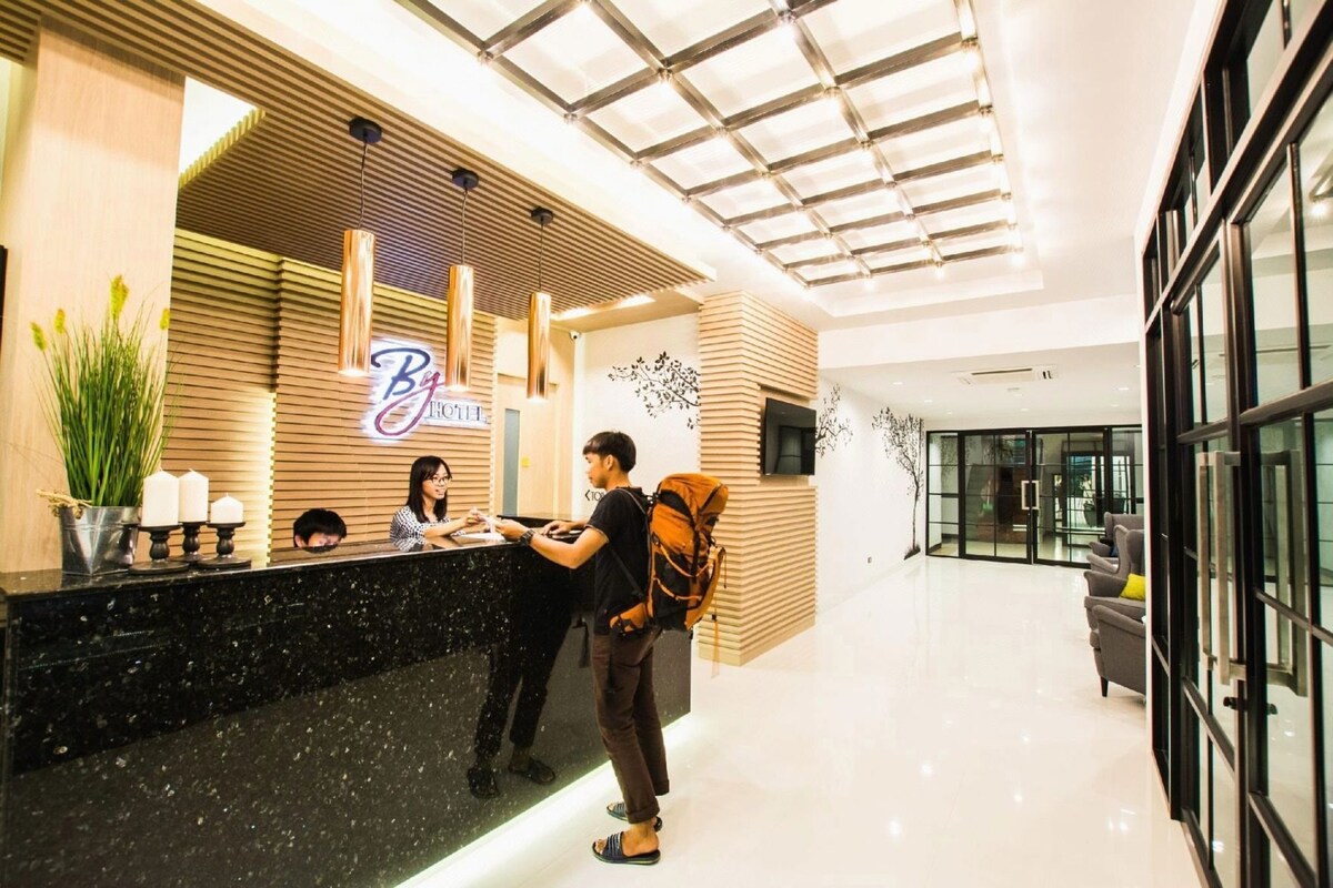 A hotel reception area with a modern design, featuring a reception desk, a plant, and a sign that reads 'Big Hotel'.