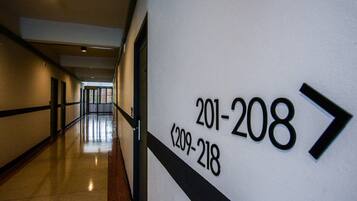 Un pasillo con señales que indican los números de habitación 201 al 208 y 209 al 218.