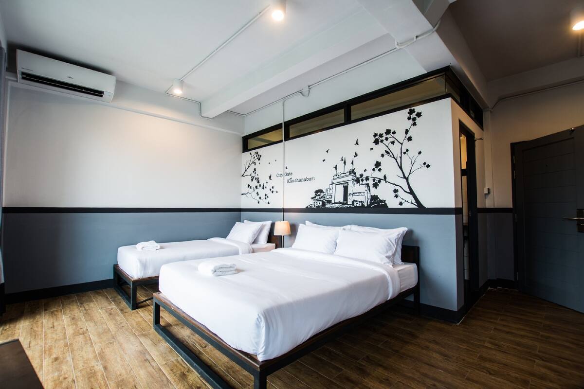 A hotel room with two beds, a wall mural, and a wooden floor.