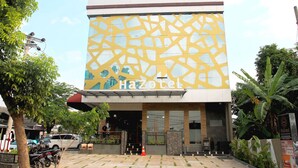 A modern building with a unique yellow and white geometric facade, a visible entrance, and a sign reading "HaZotel". - Hazotel Semarang (Semarang)