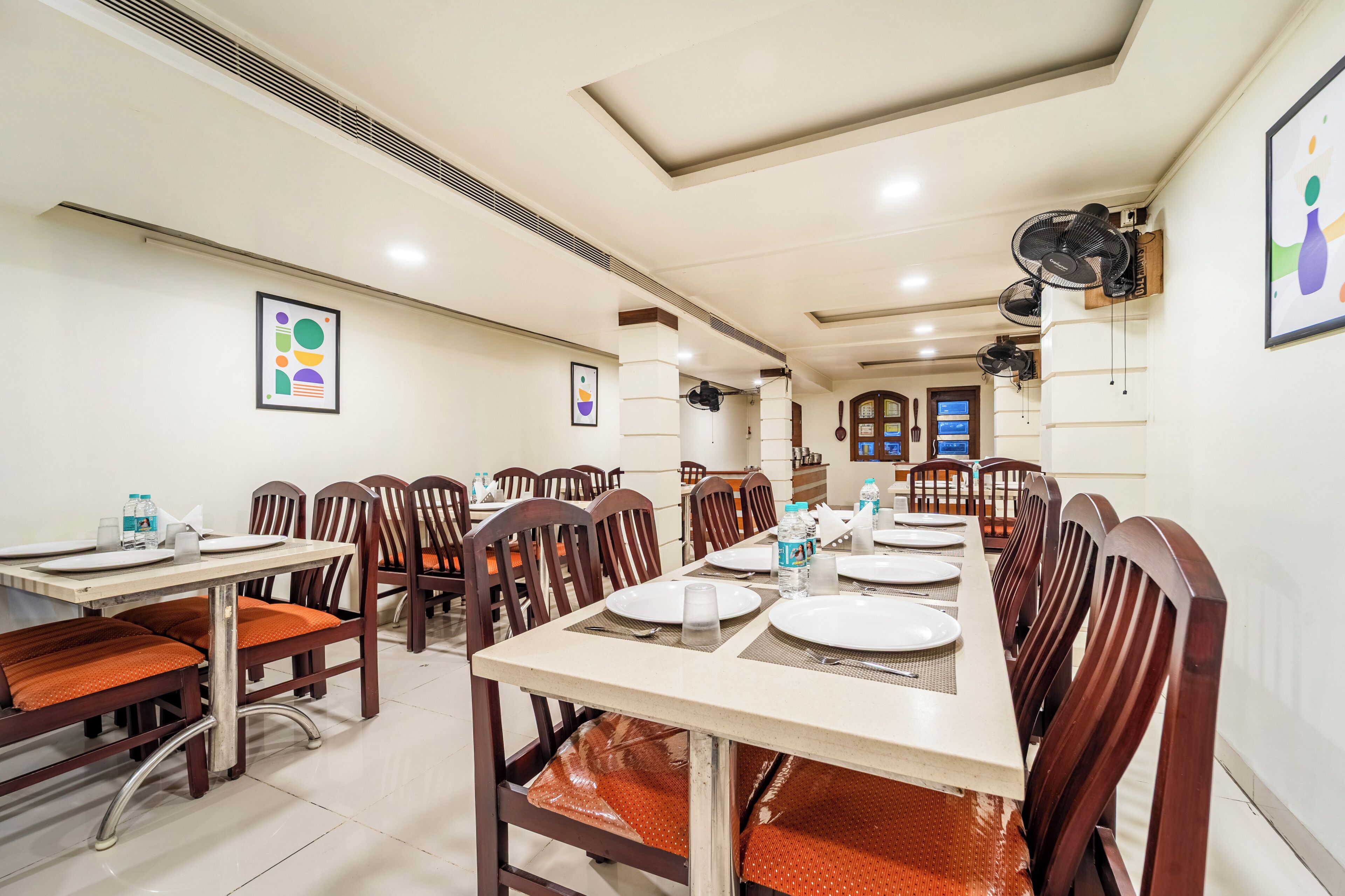 Comedor con varias mesas y sillas, equipado con botellas de agua y servilletas.