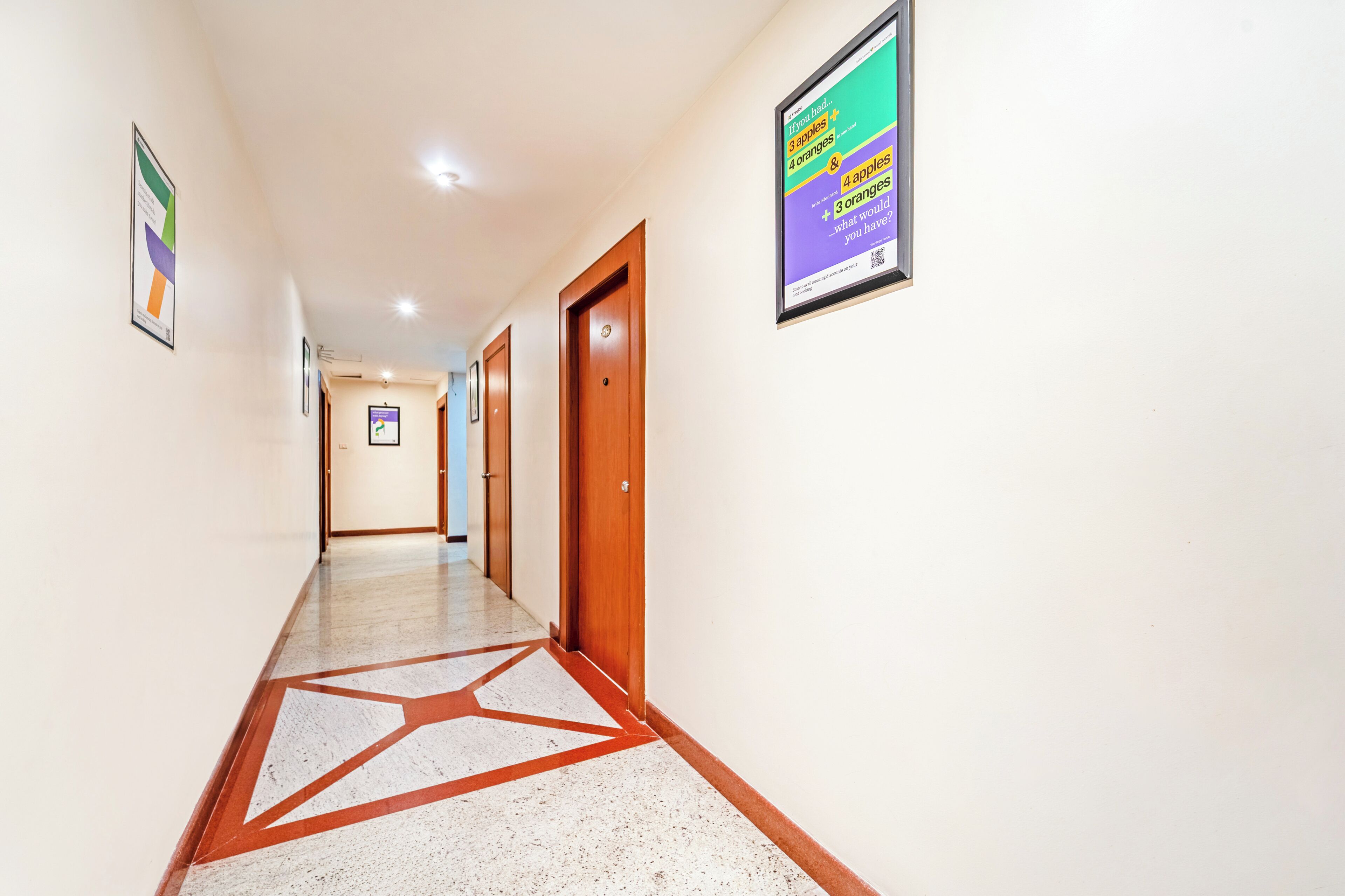 A hallway with a geometric floor pattern, wooden doors, and a poster on the wall.